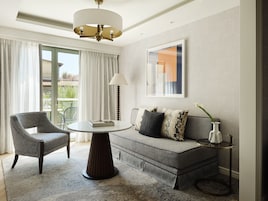 A modern living room with a sofa, armchair, round table, and a floor lamp.