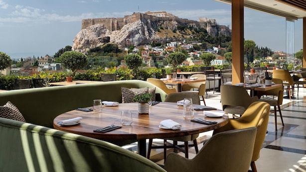 Un restaurante con vistas a una fortaleza histórica en una colina, con terraza y una decoración de estilo moderno.
