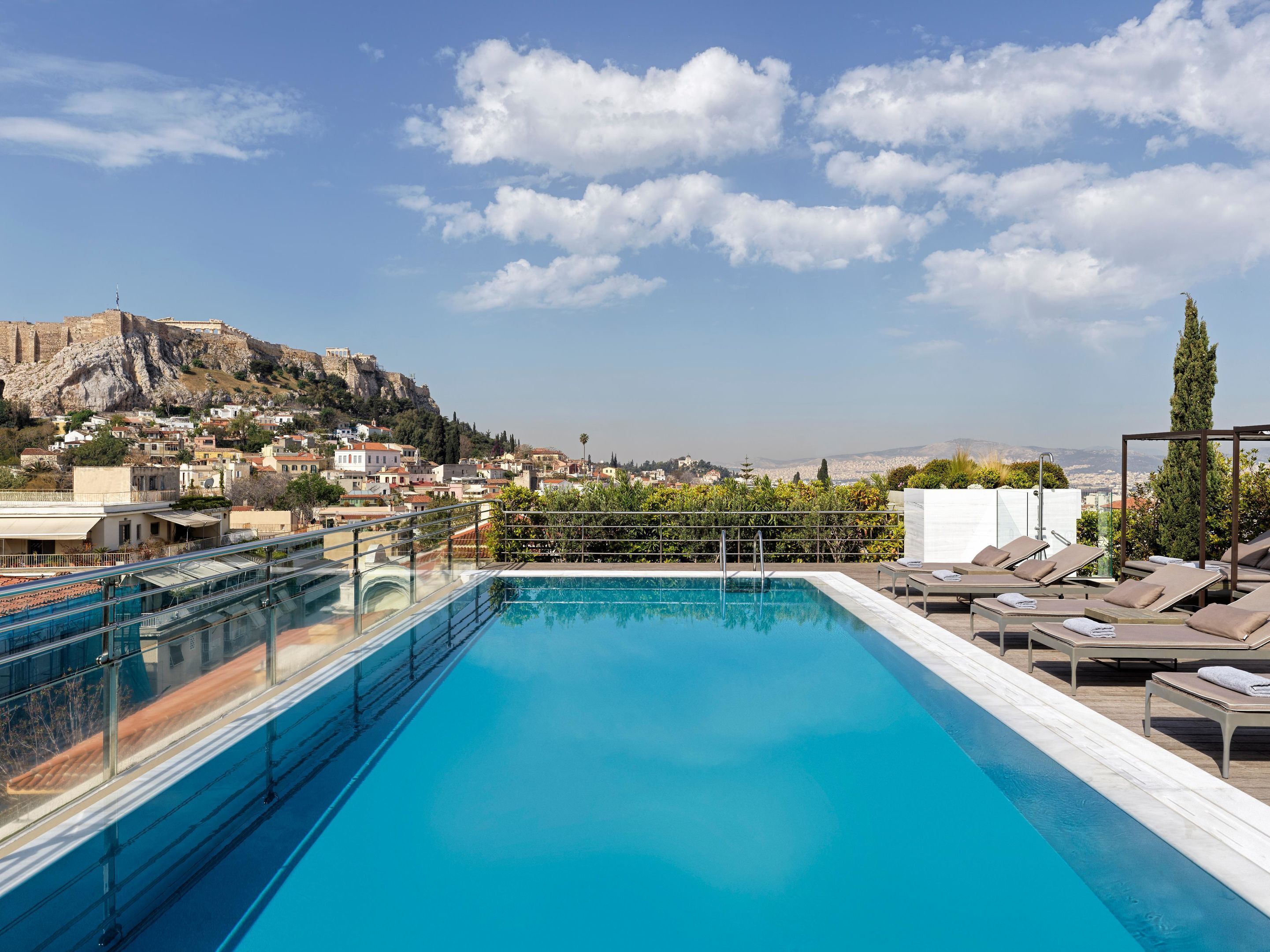 A rooftop swimming pool with a view of a historic cityscape and a mountain.