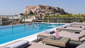 Una piscina en la azotea con sillones de descanso y vistas a un castillo histórico.