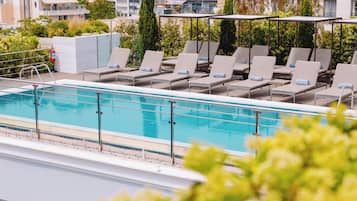 A rooftop pool area with lounge chairs and a view of the cityscape.