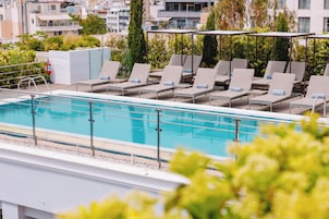 A rooftop pool area with lounge chairs and a view of the cityscape.
