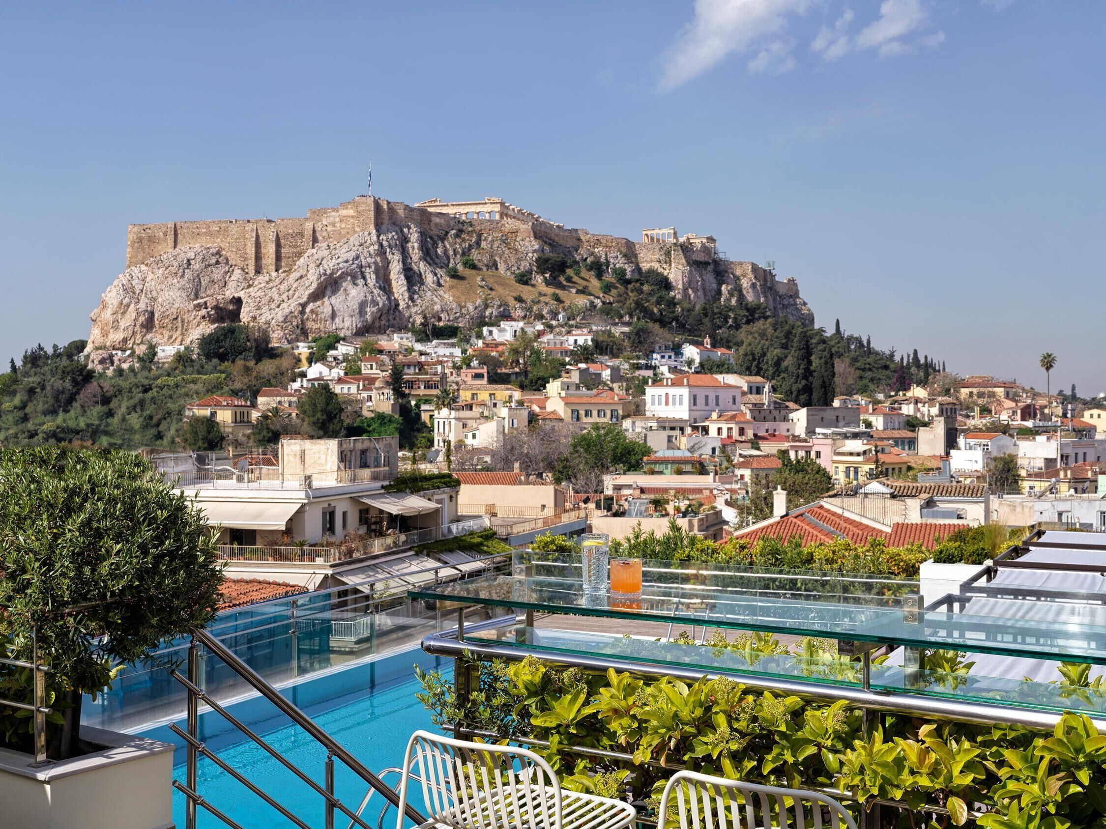 A rooftop pool with a view of a historic cityscape and a prominent hill with ancient ruins.