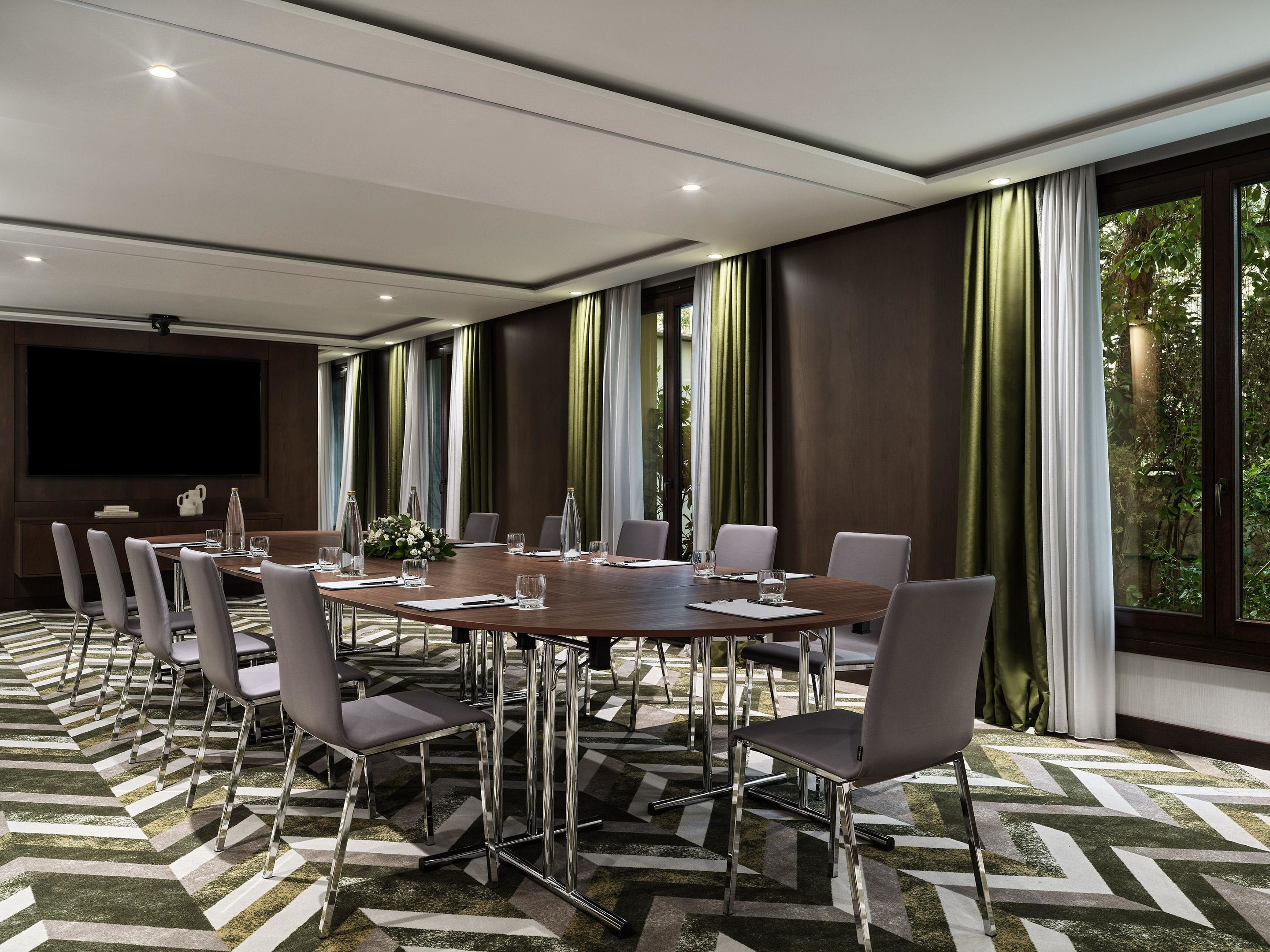 A conference room with a large table, chairs, and a flat-screen TV.