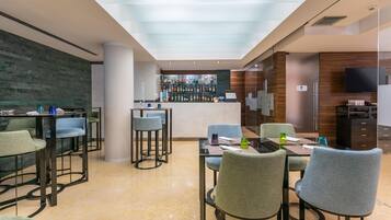 A modern hotel lobby with a bar area, seating arrangements, and a visible restroom sign.