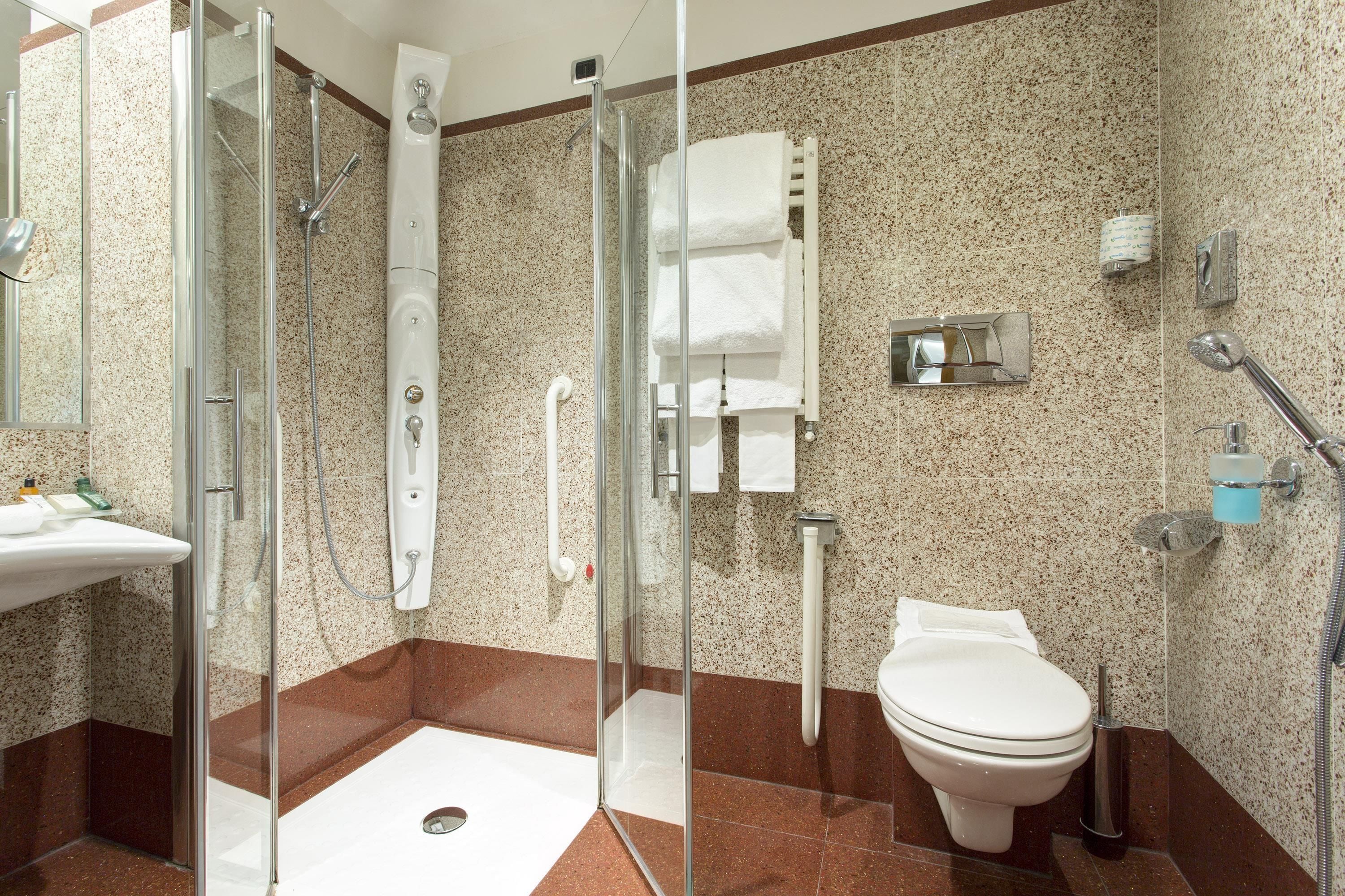 A modern bathroom with a glass shower enclosure, a white toilet, and a sink.