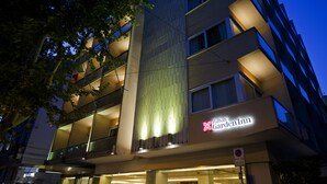A multi-story hotel with a modern facade, illuminated signage, and balconies.