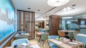 A modern dining area with tables, chairs, and a large window.