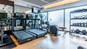 A gym with treadmills, elliptical machines, and a rack of dumbbells.