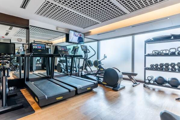 A gym with treadmills, elliptical machines, and a rack of dumbbells. - Hilton Garden Inn Rome Claridge (Rome)