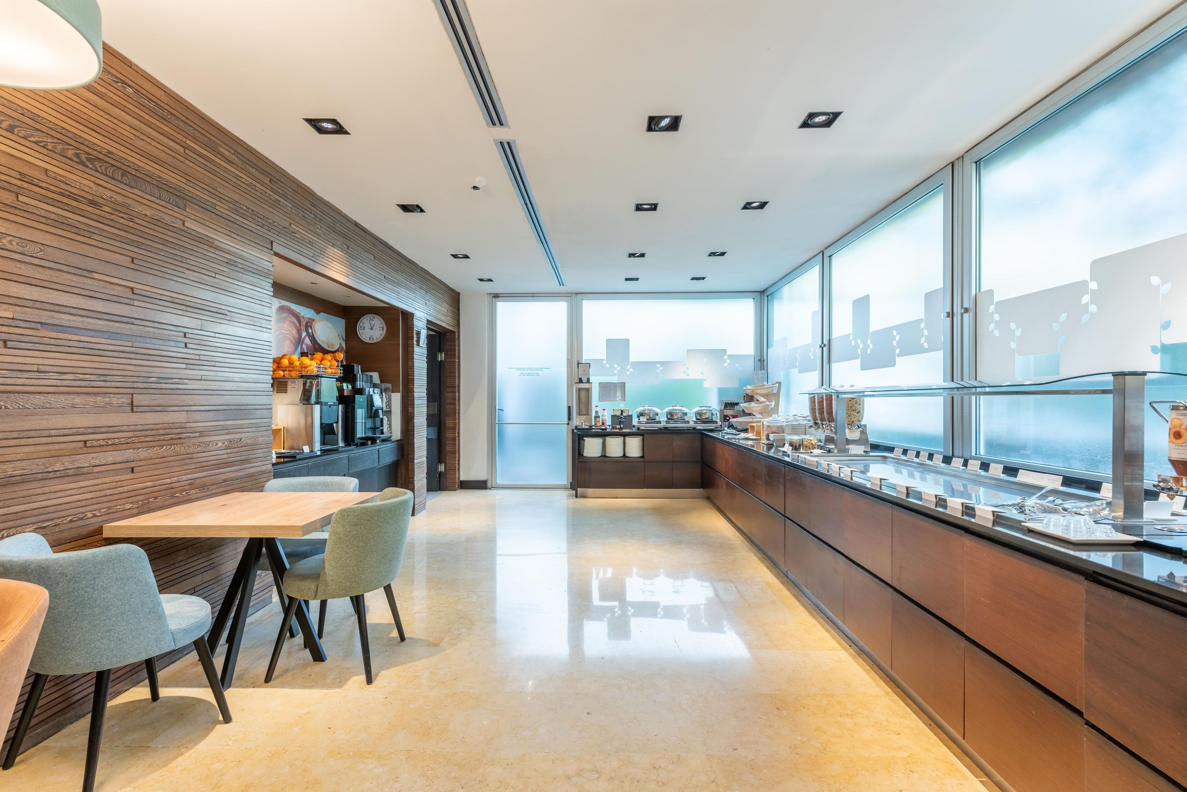 Un caffè moderno con una parete in legno, una macchina da caffè, un orologio e un banco buffet.