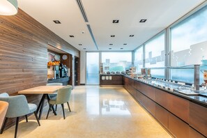 A modern cafe with a wooden wall, a coffee machine, a clock, and a buffet counter. - Hilton Garden Inn Rome Claridge (Rome)