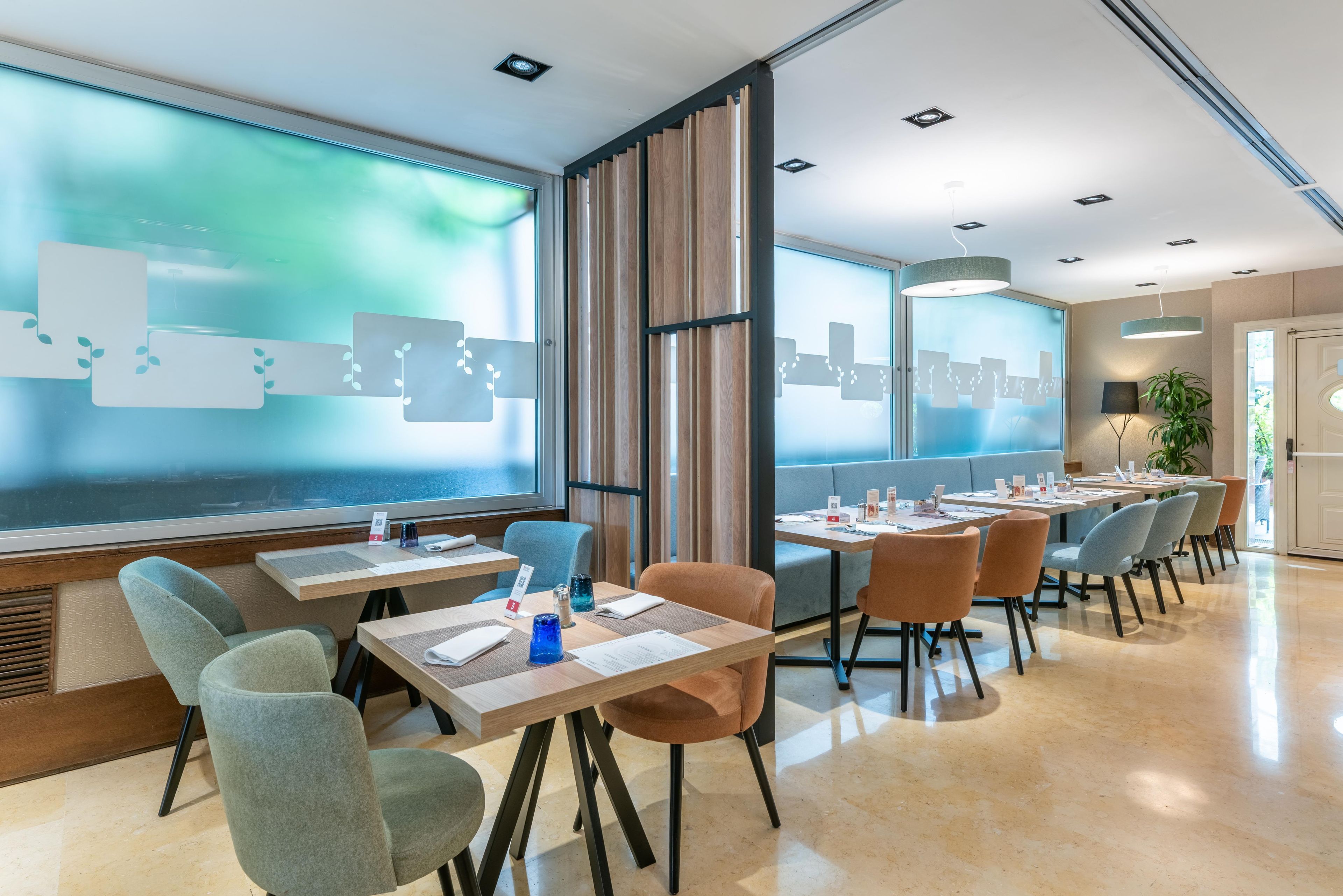 A modern dining area with tables and chairs, a cityscape view, and a large window.