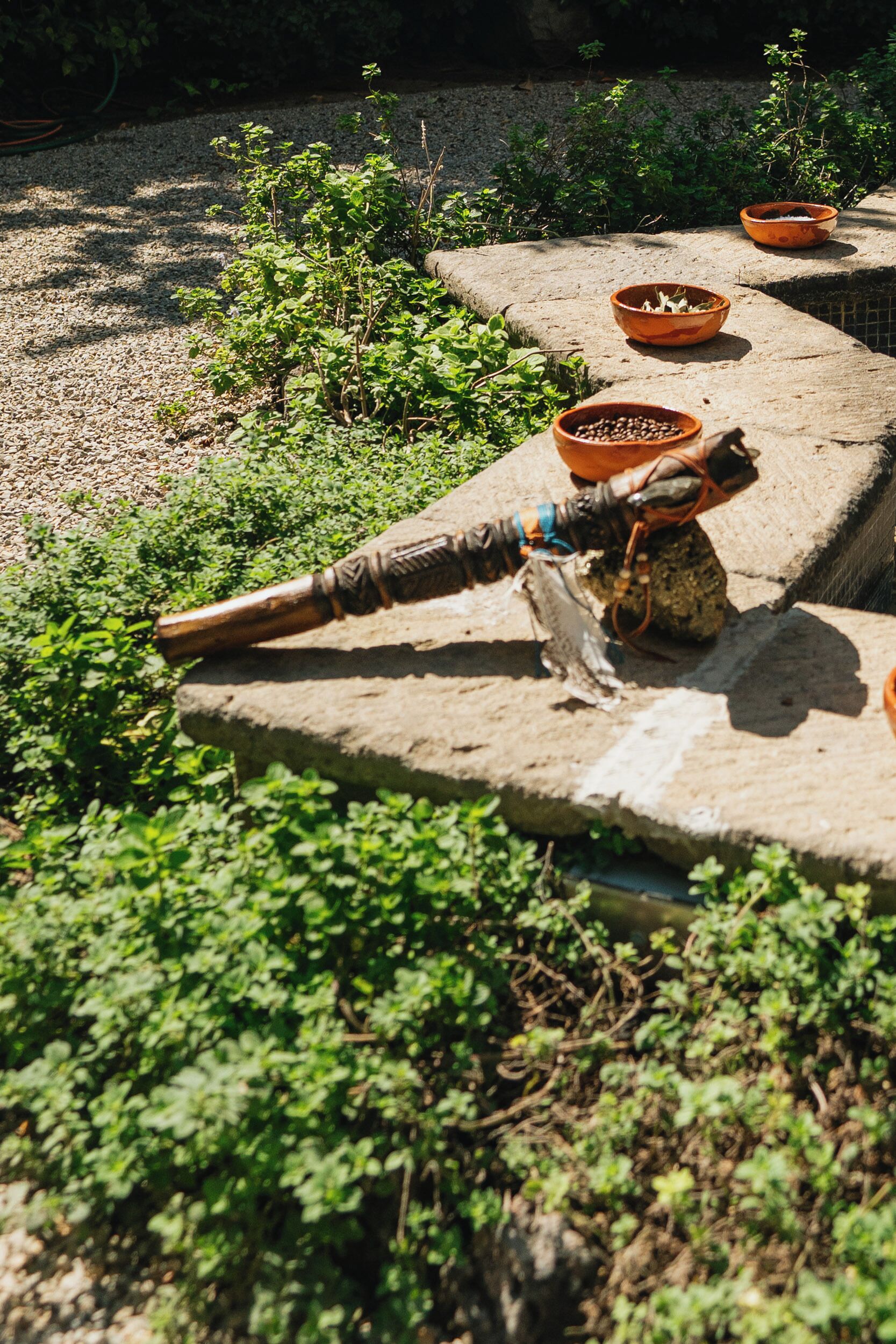 A stone ledge with terracotta bowls and a rustic metal tool.
