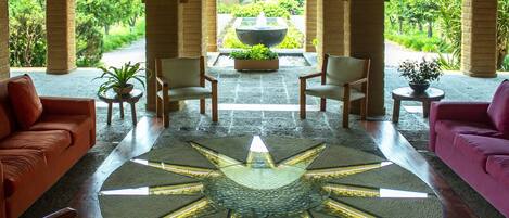 A lobby with a star-shaped floor design, two sofas, and a fountain in the background.