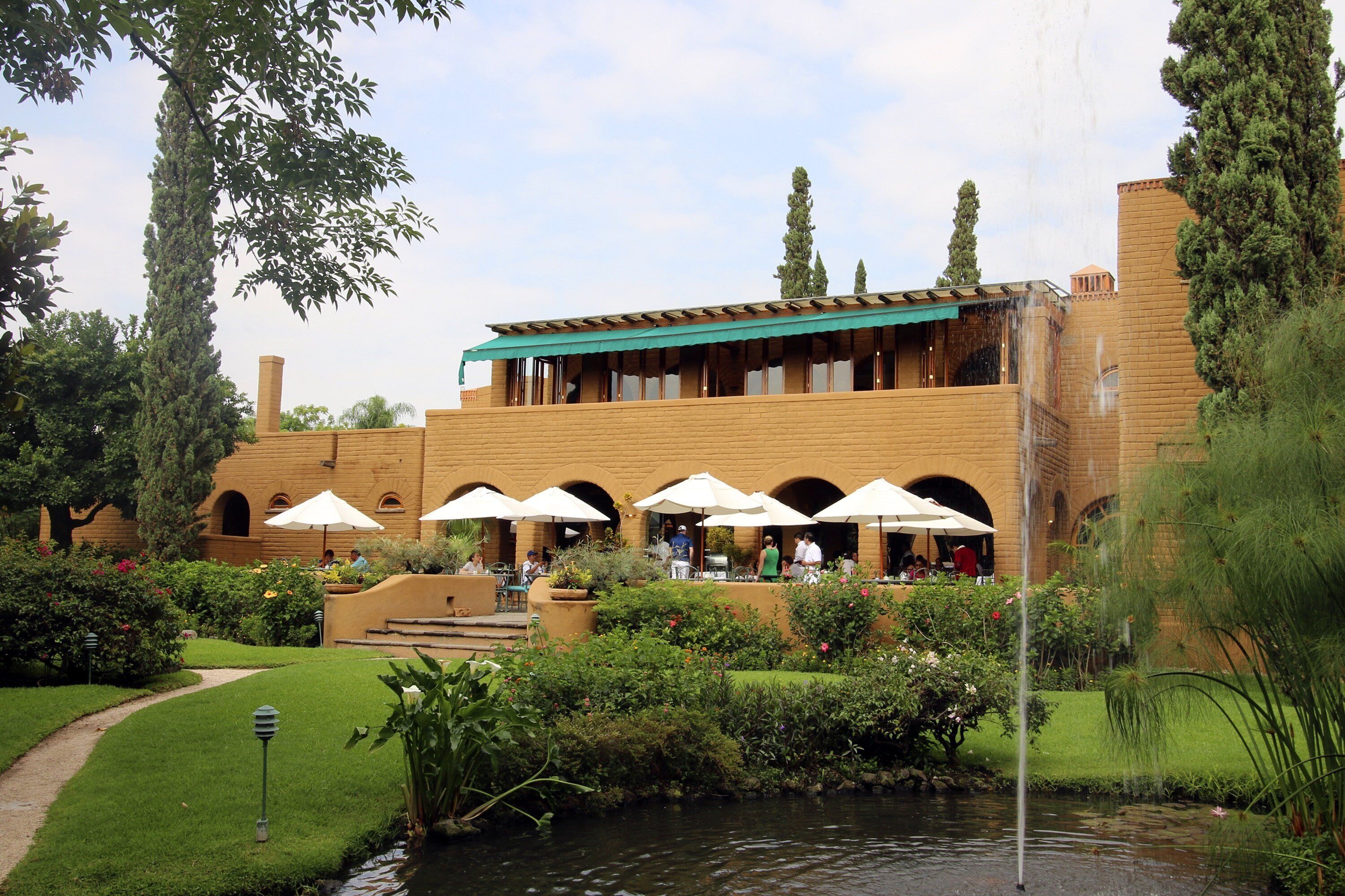 A courtyard with a pool, outdoor seating, and a building with arched windows and a green awning.
