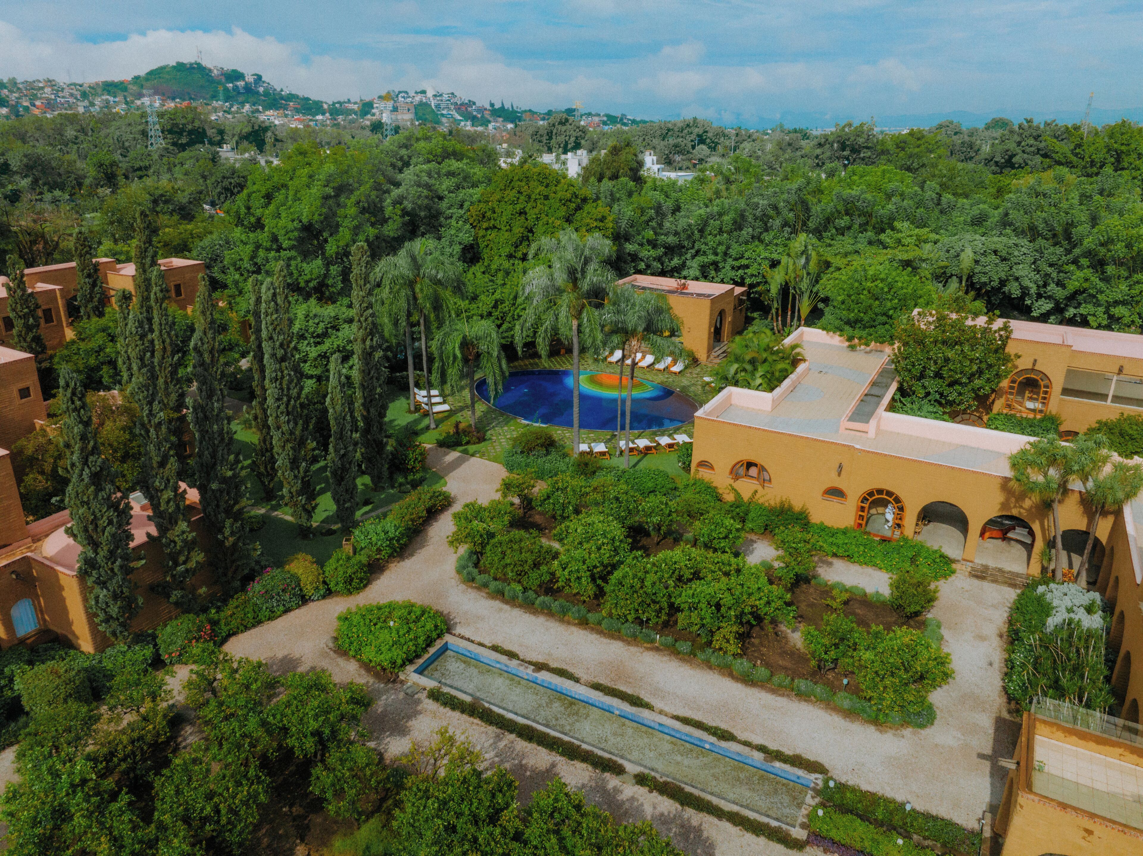 A resort with a swimming pool, lush greenery, and Mediterranean-style architecture.