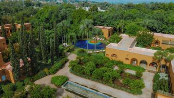 A resort with a swimming pool, lush greenery, and Mediterranean-style architecture.