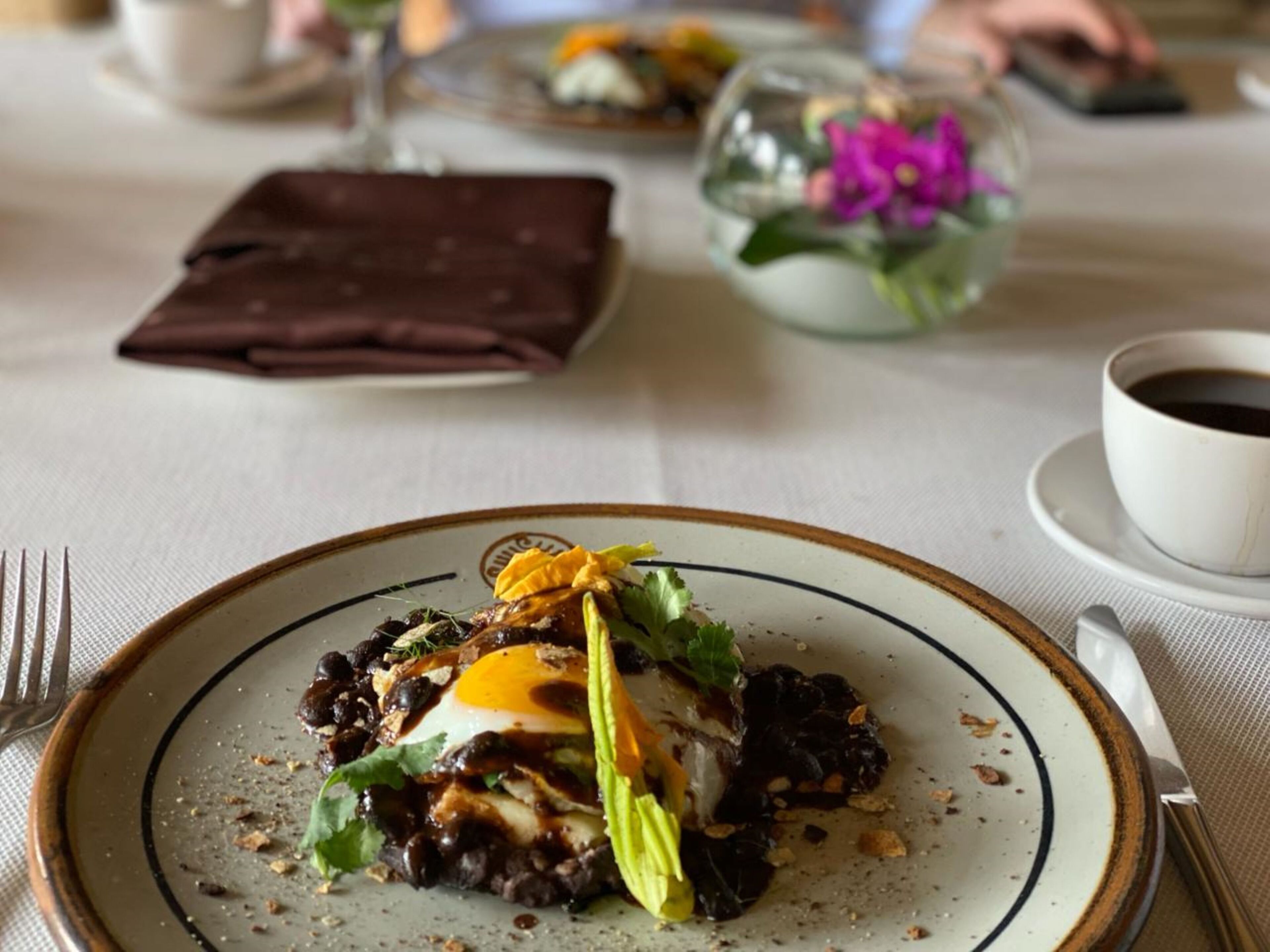 Una mesa con un plato de comida, una taza de café y una servilleta.