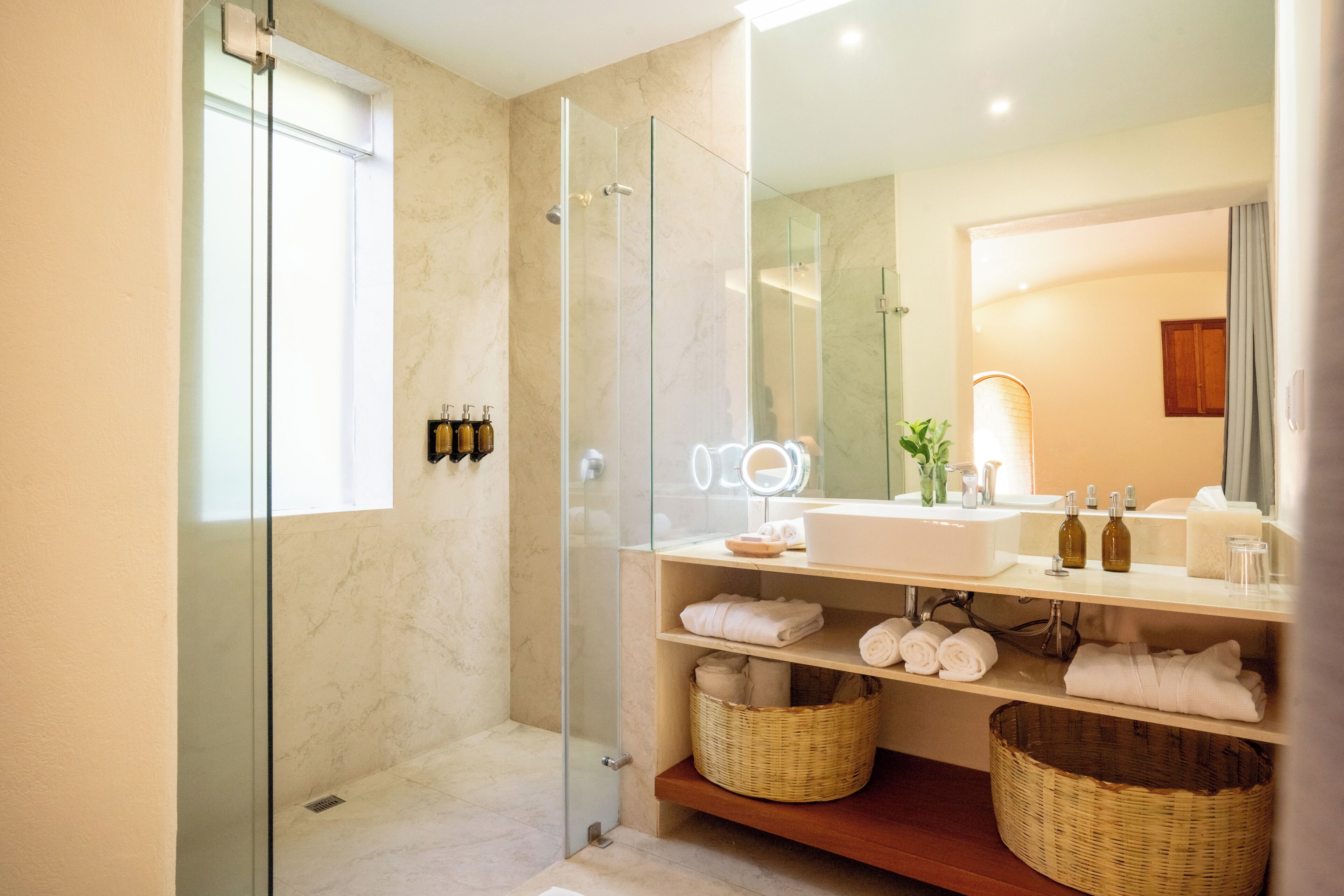 A modern bathroom with a glass-enclosed shower, a vanity with a mirror, and a sink.