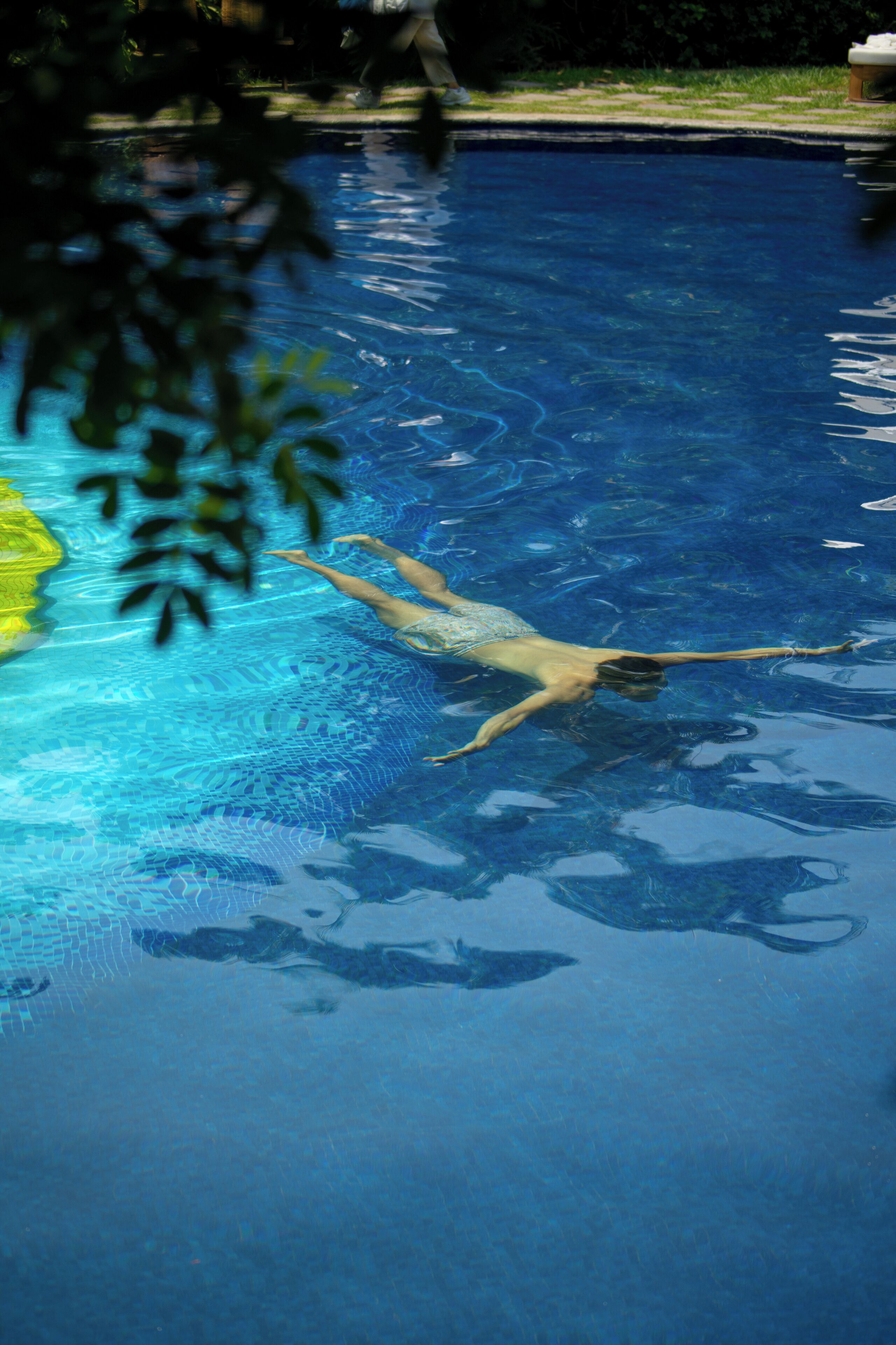 Una persona nadando en una piscina azul y cristalina.