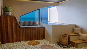 Ein modernes Interieur mit einer hölzernen Sitzbank, einem Topfpflanzen und Meerblick.