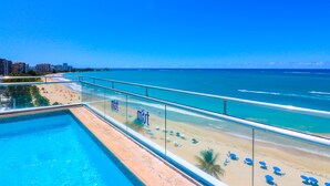 A poolside view with a beach and ocean in the background. - Aire de O:live (Carolina)