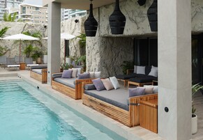 Una piscina al aire libre, sombrillas, sillones reclinables de piscina