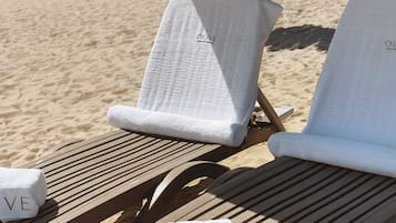 Dos sillas de playa con toallas blancas, una con la etiqueta "O:LIVE" y la otra con la etiqueta "O:LIVE HOTEL".