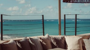 Blick auf das Meer vom Balkon mit einer Couch, einem Tisch, einer Fernbedienung und einer kleinen Pflanze auf dem Tisch.