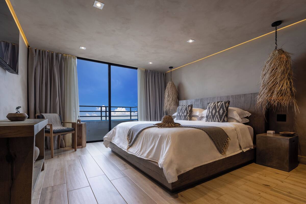 Une chambre moderne avec un grand lit, un bureau et une vue sur la mer.