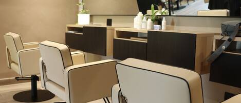 A salon with multiple chairs, a reception desk, and a large mirror.