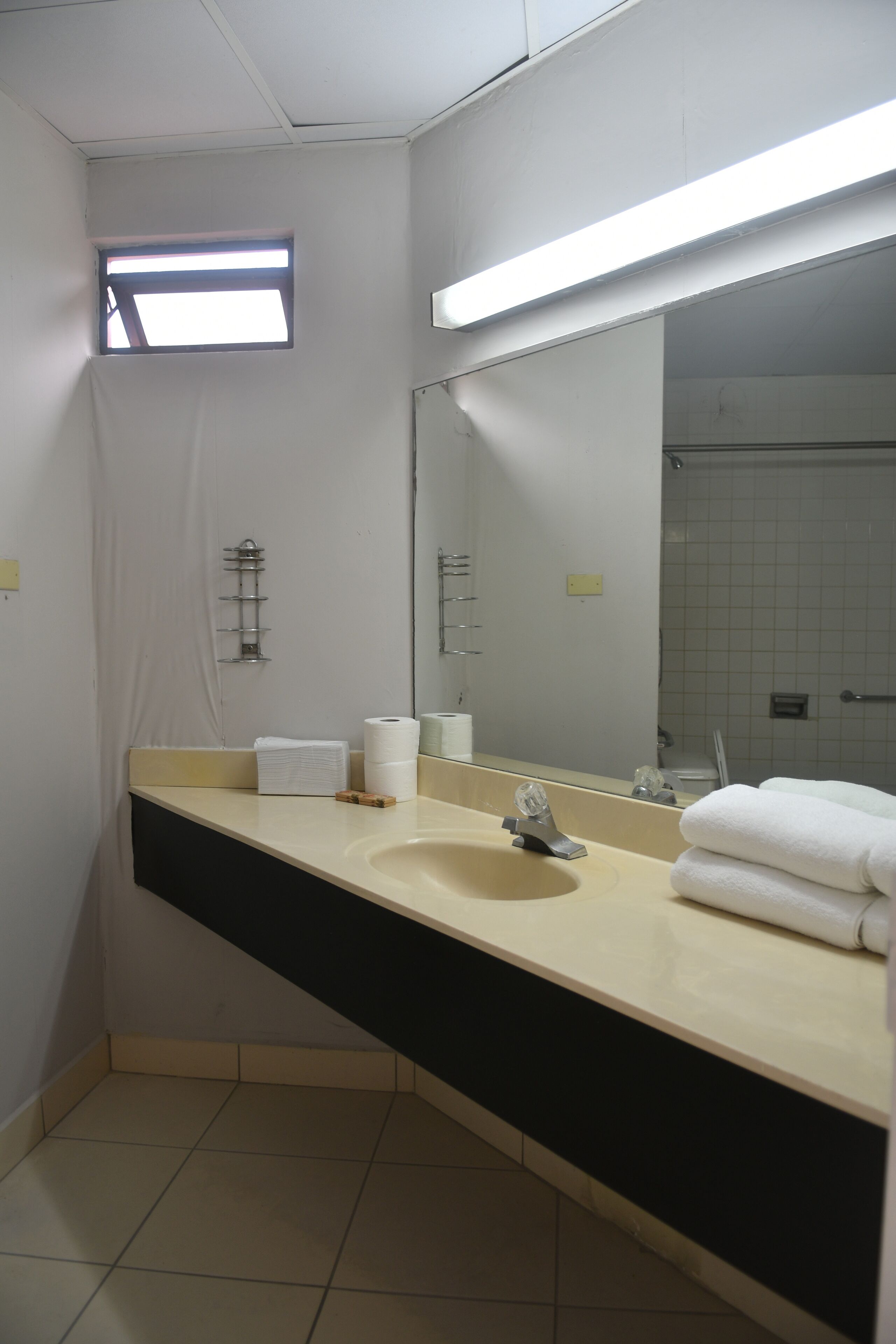 A bathroom with a sink, mirror, towel rack, and a small window.