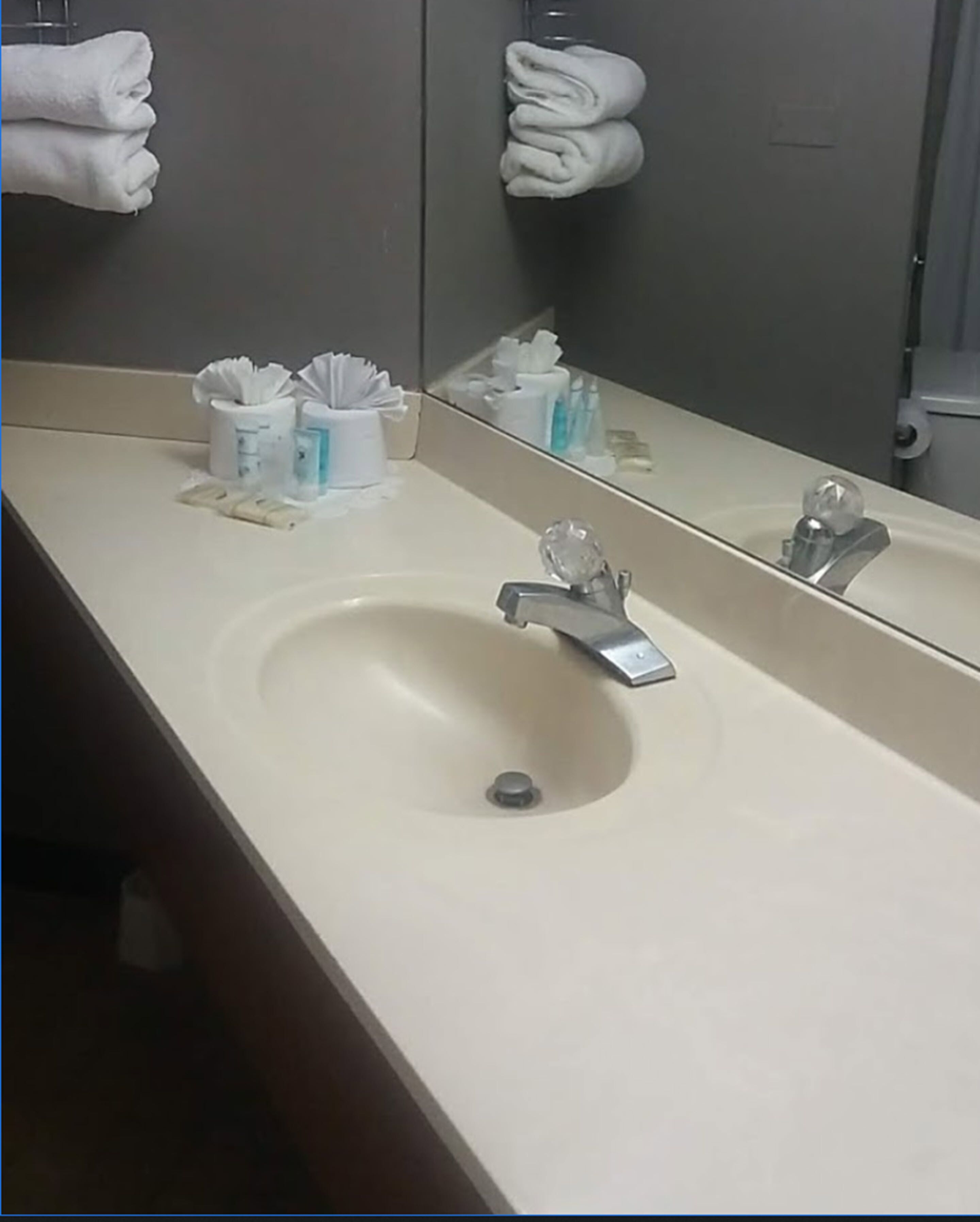 Un baño con lavamanos, espejo y perchero para toallas.