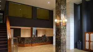 Un hall d’entrée moderne avec un comptoir d’accueil, un escalier et une grande colonne.