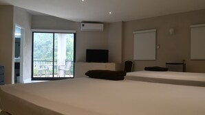 Une chambre d’hôtel avec deux lits, une télévision, un appareil de climatisation et un balcon équipé de chaises.