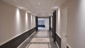 Un couloir doté d’un sol à motifs, d’un éclairage encastré et d’une porte portant l’inscription « Sortie de secours ».
