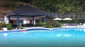 Une piscine dotée d’un pavillon abrité, de chaises longues et de parasols.