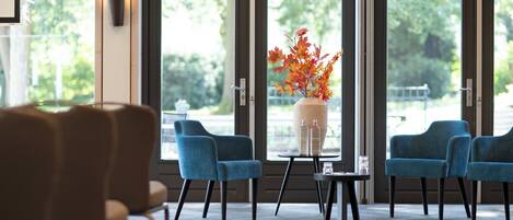 A seating area with blue chairs and a table with a vase of flowers.
