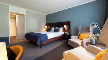 A hotel room with a bed, two bedside tables with lamps, a sofa, and a chair.