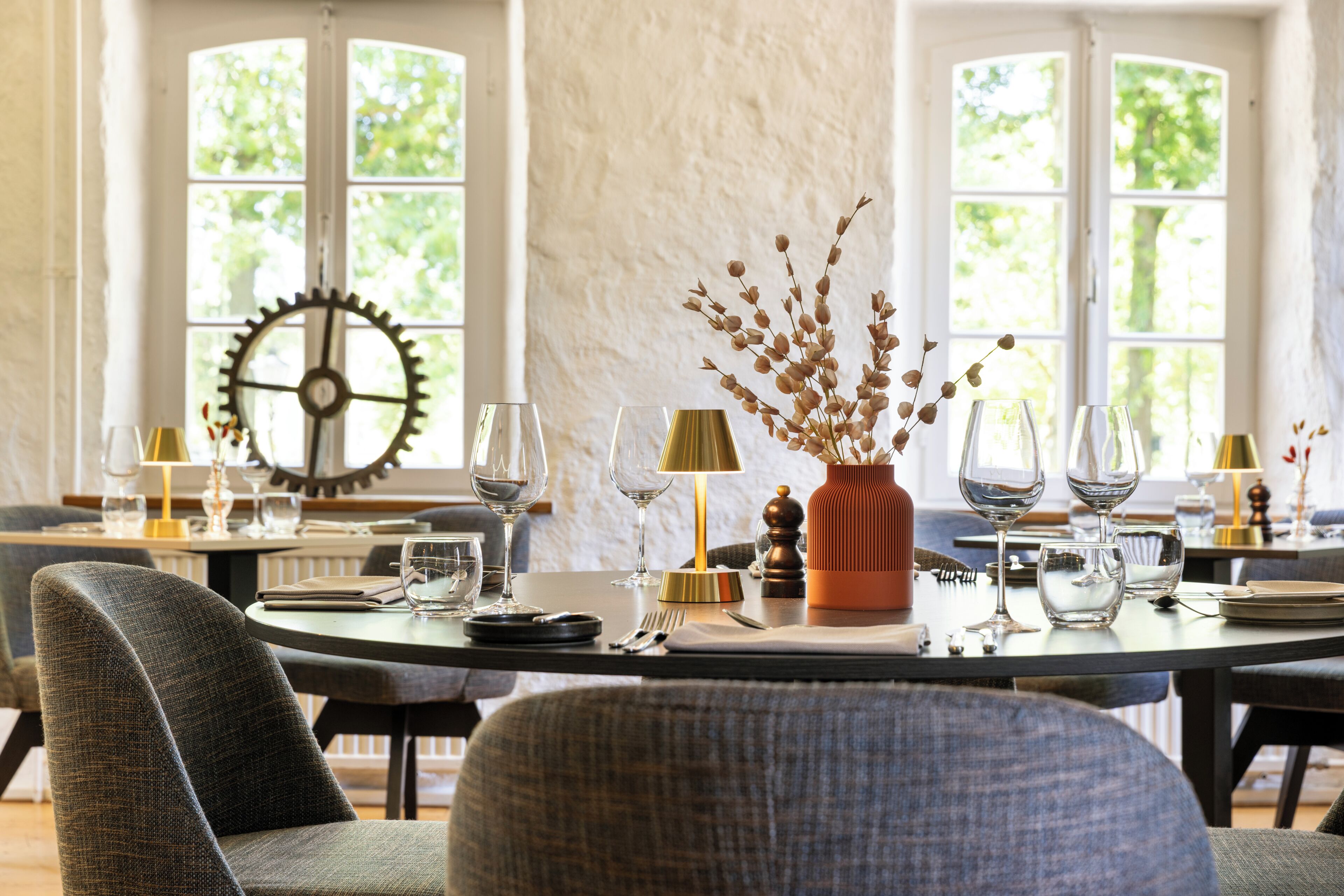 A dining area with a round table set for a meal, surrounded by chairs.