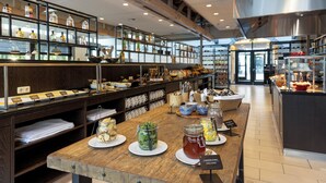 Une cuisine moderne et bien éclairée, dotée de plans de travail en bois, d’appareils électroménagers en acier inoxydable, et où une variété d’aliments et d’épices sont présentés sur des étagères et des tables.