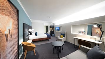 Een moderne hotelkamer met een bed, een bureau, een bank, een stoel en een televisie.