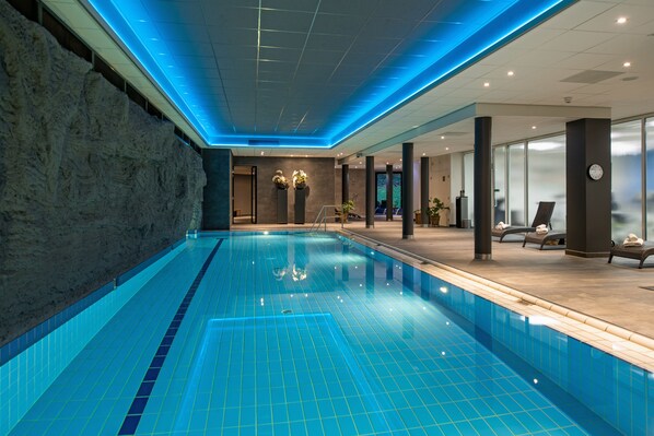 Una piscina techada, sillones reclinables de piscina