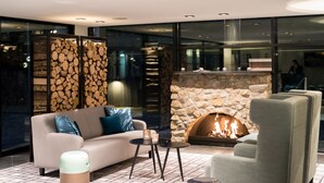 Un salon moderne avec une cheminée en pierre, un canapé, des fauteuils et une table basse.