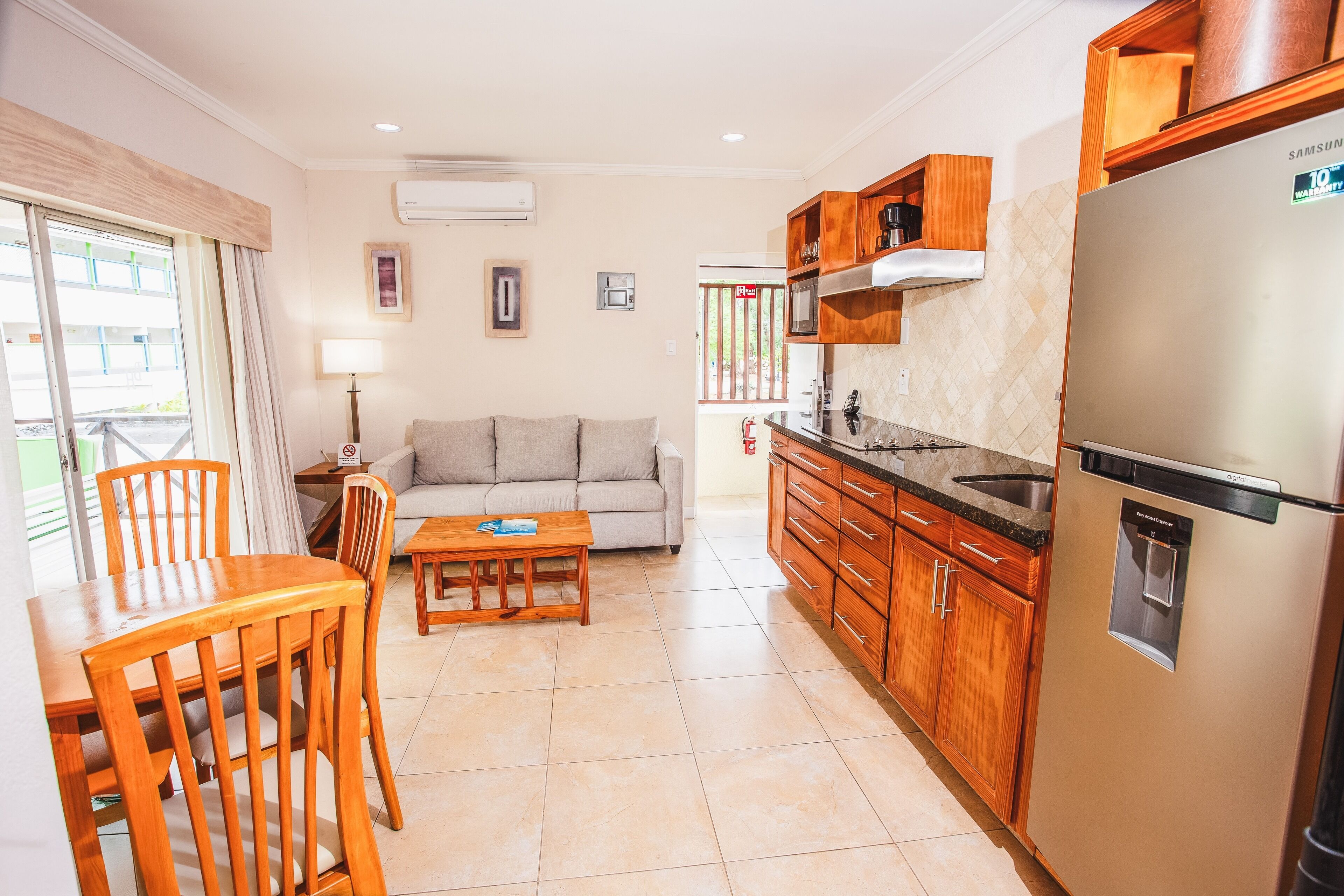 A compact kitchen with wooden cabinets, a stainless steel refrigerator, and a dining area with a table and chairs.