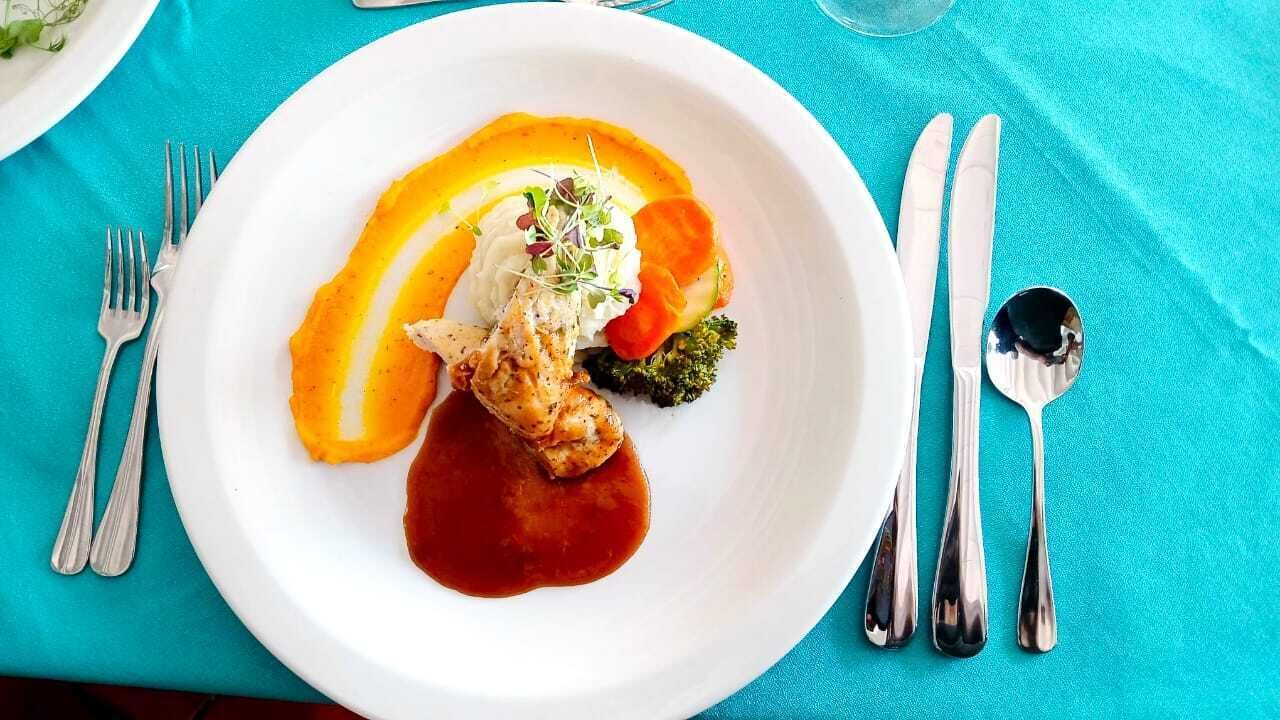 A white plate with food on a turquoise tablecloth.