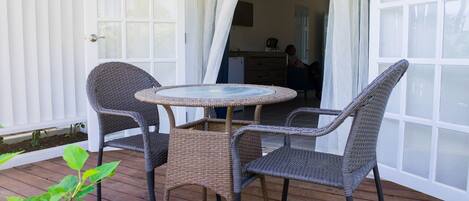 Un patio cubierto con muebles de mimbre y una mesa con superficie de vidrio.