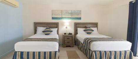 A hotel room with two beds, a nightstand, a painting, and a window with curtains.