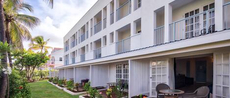 Ein Hotel mit mehreren Balkonen, einer überdachten Außenbereich-Sitzgelegenheit und einem gepflegten Garten.